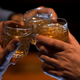 Three hands holding glasses of spirits up in a toast